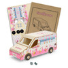 A wooden model of an ice cream van in pink and white, alongside assembly instructions and decorative stickers.