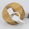 A bamboo circular base with a retractable charging cable featuring white connectors for USB-C and Lightning.