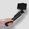 A black selfie stick tripod held in a hand, featuring a phone holder at the top.