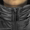 A close-up of a black puffer vest featuring a zippered collar and a logo on the zipper.