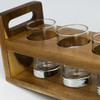 A wooden tray with a handle holds three clear glass tumblers, showcasing a rich brown colour.