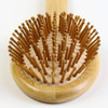 A bamboo hair brush with a round base and wooden bristles, featuring a natural bamboo handle.