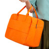 An orange felt travel bag with two handles and a zipped compartment, held by a person.