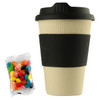 A reusable 12oz bamboo coffee cup in cream with a black sleeve, accompanied by a bag of colourful jelly beans.