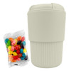 A reusable coffee cup in light beige, accompanied by a bag of colourful jelly beans. The cup features a logo.