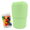A mint green reusable coffee cup with a textured grip, accompanied by a pack of colourful jelly beans.