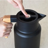 A drink bottle in black with a wooden handle and a sleek design, featuring a push button lid.