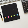 A black sticky note pad with colourful dots in pink, orange, yellow, green, and blue. Includes a logo.