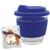 A clear glass coffee cup with a blue silicone lid and grip, accompanied by a bag of mixed lollies.
