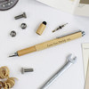 A bamboo tool pen in natural colour, accompanied by mechanical parts and a wrench on a textured surface.