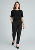 A woman wearing black slacks and a black top, walking confidently with her hands in the pockets of the pants.