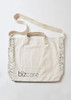 A beige unisex tote bag featuring a patterned edge and a logo. It has two carrying handles and a shoulder strap.