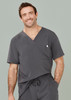A man wearing a grey V-neck scrub top with a pocket. The scrub top features a loose fit and casual style.
