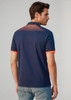 A men's short sleeve polo in navy blue with orange accents and a patterned design on the back. Features branding.