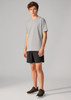 A young person wearing grey sports shorts and a grey t-shirt, paired with black athletic shoes. The shorts have a logo.
