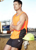 A man wearing an orange high-visibility singlet stands beside a yellow hard hat and gloves.