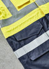 A bright yellow and dark navy jacket featuring reflective strips and multiple pockets, with a logo present.