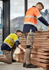 Two men wearing high-visibility work shirts in orange and yellow, with stretch pants, are arranging wooden boards indoors.