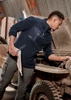 A man in a navy lightweight 1/4 zip polar fleece, working on a vehicle, with a logo on the garment.