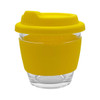 A reusable glass coffee cup with a bright yellow silicone sleeve and lid, featuring a clear glass body.