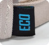 A close-up of a beige cap featuring a small black tag with a blue logo, indicating it is eco-friendly.