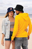 Two individuals on a beach, one wearing a navy bucket hat and the other in a black bucket hat, both casual outfits.