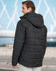 A unisex sustainable seamless parka jacket in black with a hood and 3D cut, shown from the back.