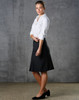 A black women's pleated skirt made from wool stretch, styled with a white shirt and black shoes, set against a grey background.