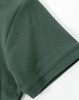 A close-up of a dark green cotton stretch polo shirt sleeve, featuring a smooth fabric texture and a logo.