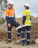 Two workers in high-visibility workwear, wearing orange and yellow shirts with navy pants, on a construction site.