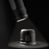 A black Swiss Peak 4-in-1 speaker illuminated by a flashlight, showcasing its sleek design and functionality.