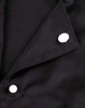A close-up of a black chef jacket featuring two white exchangeable buttons on the collar.