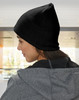 A beige cable knit beanie with a fleece headband, worn on a person’s head, seen from the side.