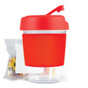 A reusable coffee cup in vibrant red with a lid and a sip spout, accompanied by a small packet of colorful jelly beans.
