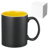 A ceramic coffee mug with a matte black exterior and yellow interior, accompanied by a plain white box.