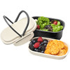 A plastic and wheat straw lunch box in cream and black, featuring two compartments for salad and snacks.