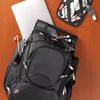 A black backpack with multiple compartments, a laptop, and a pouch containing cables and accessories.