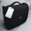 A black luggage tag attached to a stylish black bag, featuring a logo and an empty information panel.