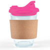 A reusable coffee cup features a clear glass body, a pink snap lid, and a cork band for grip and insulation.