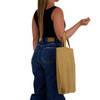 A woman holds a mustard yellow eco-friendly shopping bag with short handles, wearing a black top and blue jeans.