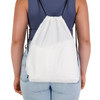 A white drawstring backpack with black straps, shown from the back on a person wearing a fitted top and jeans.