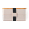 A Stax Eco Lunch Box in soft pink with a bamboo lid and a black elastic strap for secure closure.