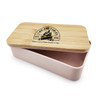 A pink lunch box with a bamboo lid and a logo on top, featuring a two-compartment design.