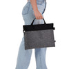 A grey felt satchel with a black top, featuring handles and a zipper, being held by a person.