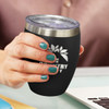 A drink bottle with a black exterior and stainless steel rim, featuring a logo. It is held in a hand with teal nail polish.