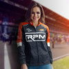 A woman wears a black and orange softshell jacket with a logo, showcasing a stylish design.