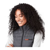 A grey lightweight packable insulated puffer vest with a black collar and a logo on the front, worn by a smiling woman.