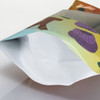 A vibrant, extra-large foil stand-up pouch with a decorative design and a white interior. Features a logo.