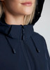 A close-up of a woman wearing a navy blue jacket with a hood, featuring a zip and adjustable drawstrings.