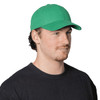 A green cap made of organic cotton twill, featuring a curved brim and an adjustable strap at the back.